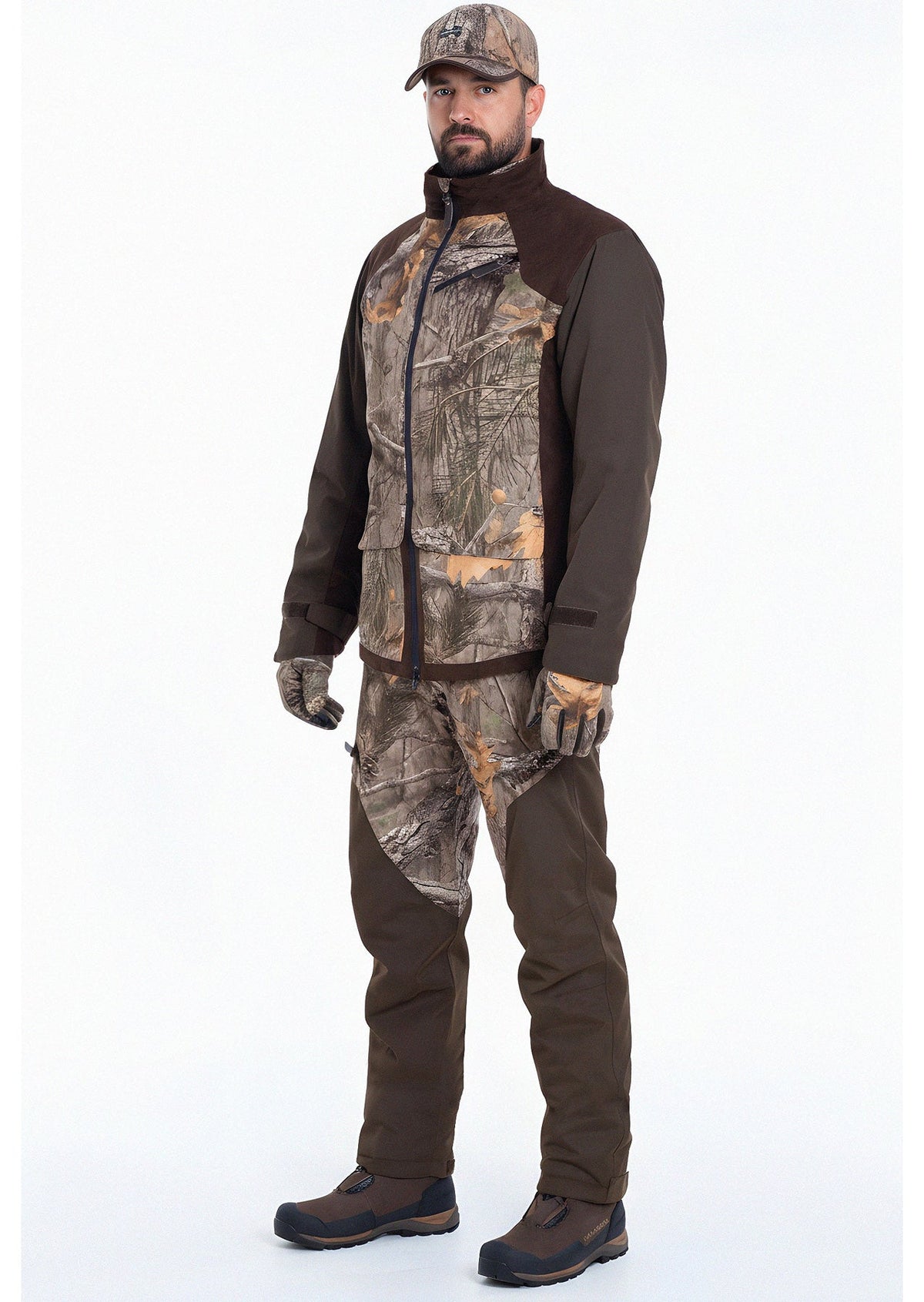 Ein Mann steht mit dem Gesicht nach vorne in der Fusion 3DX Tarnjacke Jagd von Hillman mit passender Hose, Hut, Handschuhen und braunen Stiefeln vor einem schlichten weißen Hintergrund.