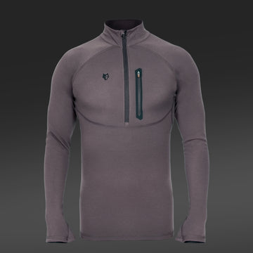 Ein graues Hillman 2BL Merino Langarmshirt auf dunklem Farbverlaufshintergrund hat lange Ärmel, einen Viertelreißverschluss, ein kleines Logo auf der linken Brust und eine Reißverschlusstasche auf der rechten Brustseite.