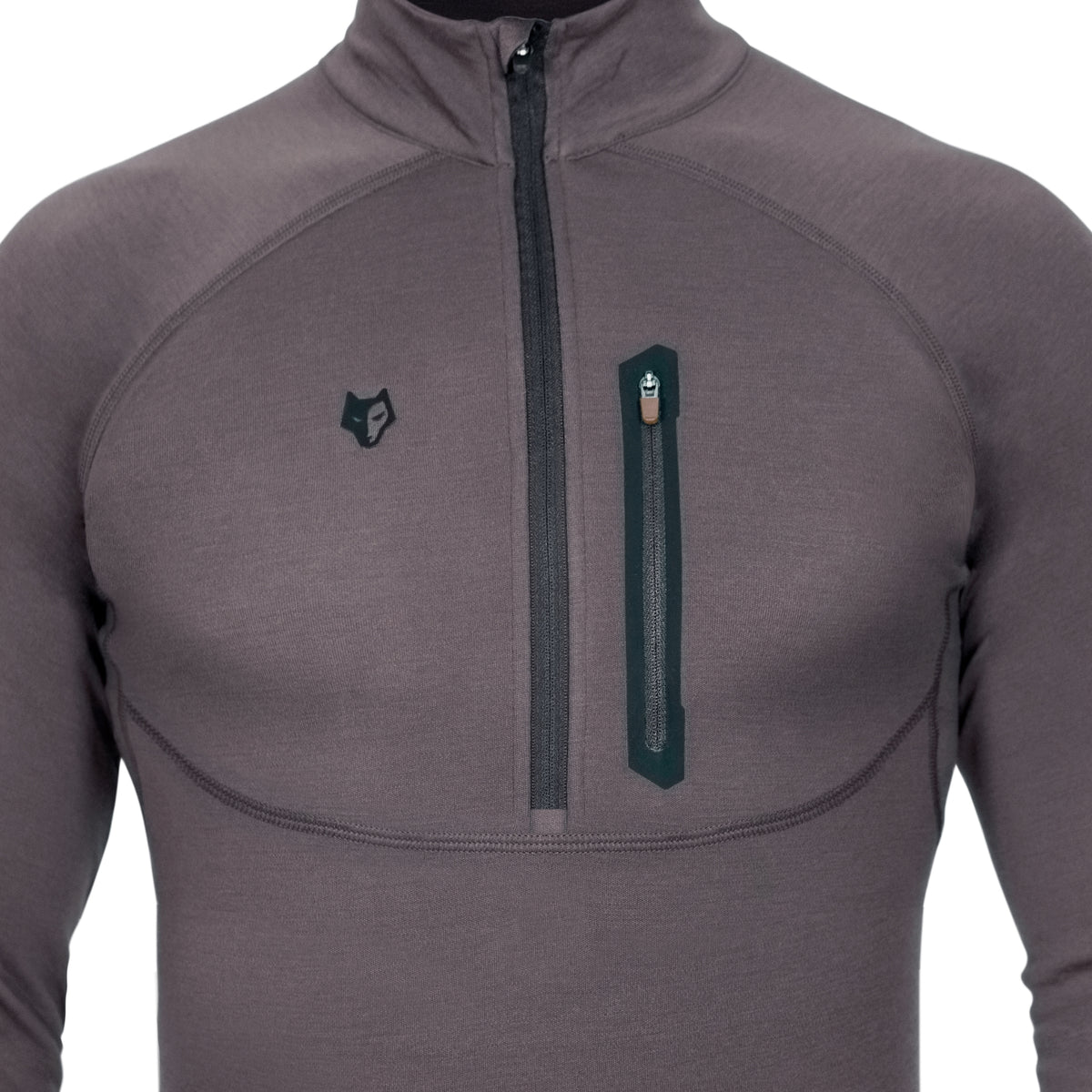 Nahaufnahme einer Person, die das Hillman 2BL Merino Langarmshirt mit Reißverschluss-Brusttasche und hohem Kragen trägt. Das dunkelgraue Design mit sichtbaren Nähten und schwarzem Wolfslogo bietet Stil und Funktionalität sowie ein innovatives Wärmeregulierungssystem für perfekte Thermoregulierung.
