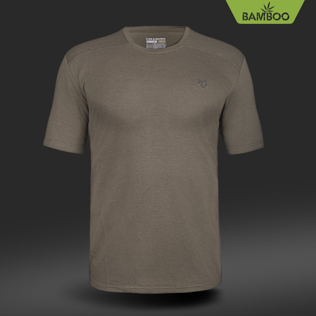Das Hillman 1UL Kurzarm-T-Shirt in Khakigrün hebt sich von dunklem Hintergrund ab und besticht durch sein dezentes Brustlogo und das Bambus-Label. Das kurzärmlige Jagd-T-Shirt aus Bambusfaser bietet eine antibakterielle, lässige und bequeme Passform.
