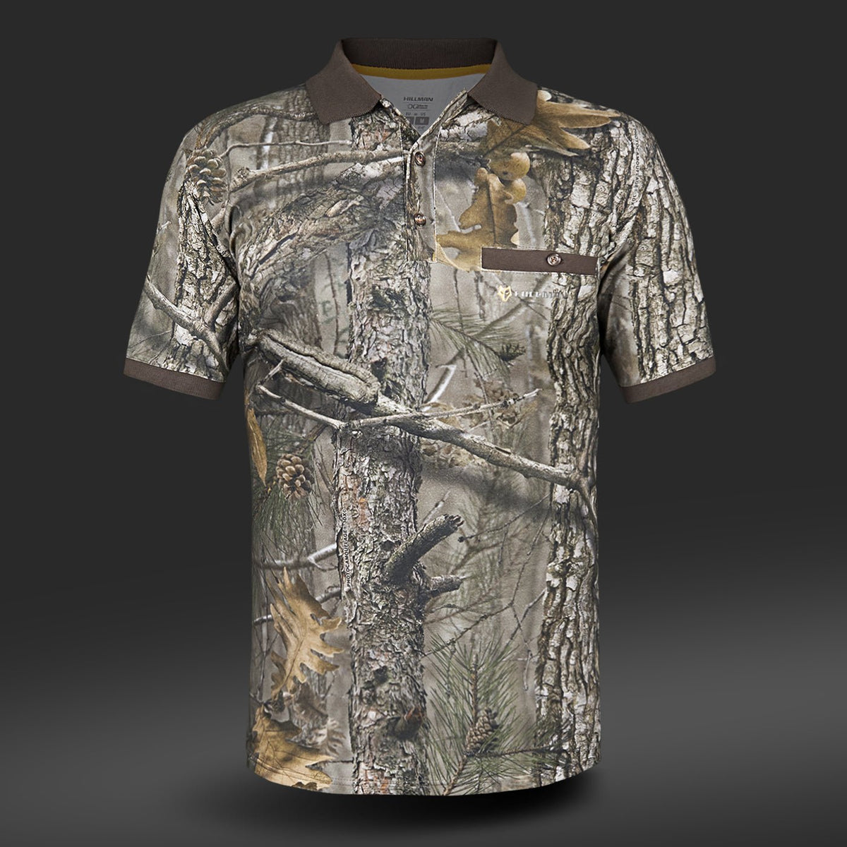Das Hillman Poloshirt Kurzarm – DGT Baumwolle Polo Jagd T-Shirt besticht durch ein Camouflage-Design mit Baumrinde, Blättern und Tannenzweigen. Es verfügt über Digitaldruck-Technologie, einen dunklen Kragen und eine geknöpfte Brusttasche auf einfarbigem grauem Hintergrund für modernen Flair.