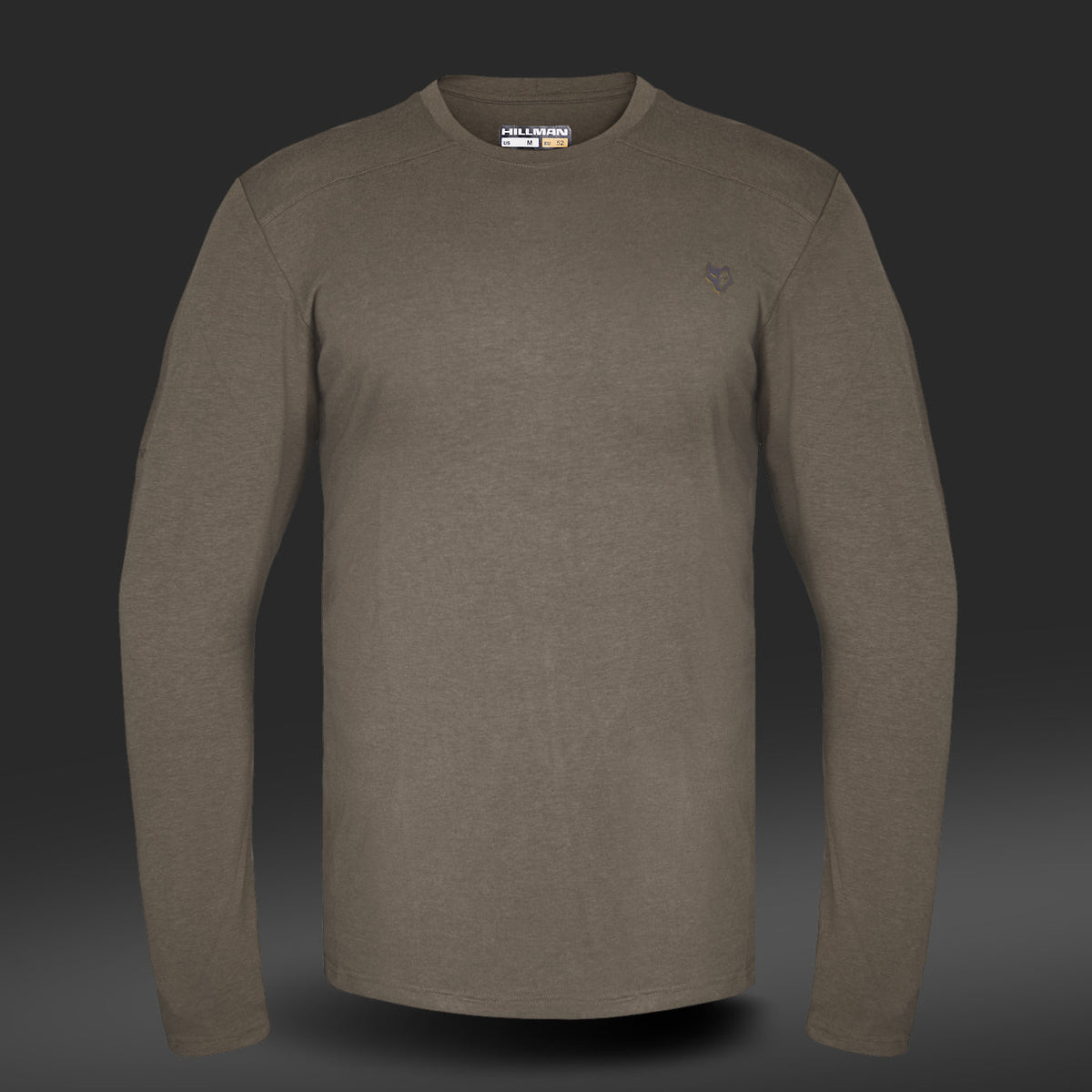 Das 1UL Langarmshirt Bambus von Hillman ist ein olivgrünes Langarmshirt mit kleinem Logo-Stick auf der linken Brust und rundem Ausschnitt. Hergestellt aus Bambusfaser, bietet es Feuchtigkeitsregulierung für optimalen Tragekomfort und besticht durch sein lässiges und schlichtes Design auf dunklem Farbverlaufsgrund.