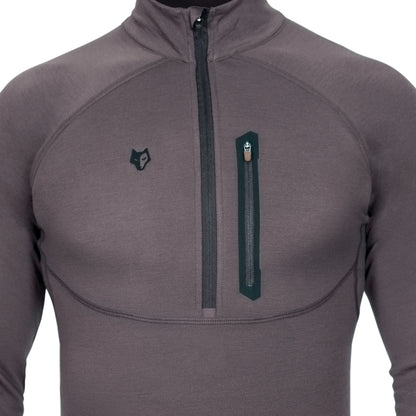 Nahaufnahme einer Person, die das Hillman 2BL Merino Langarmshirt mit Reißverschluss-Brusttasche und hohem Kragen trägt. Das dunkelgraue Design mit sichtbaren Nähten und schwarzem Wolfslogo bietet Stil und Funktionalität sowie ein innovatives Wärmeregulierungssystem für perfekte Thermoregulierung.