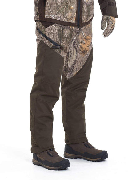 Nur die untere Körperhälfte ist vor weißem Hintergrund sichtbar. Hillmans Jagdhose Fusion Camouflage Winterhose in Grün und Braun mit passenden Handschuhen ist zu sehen. Die Tarnjacke verfügt über eine wasserdichte Atmotec-Membran für optimale Wasserdichtigkeit.