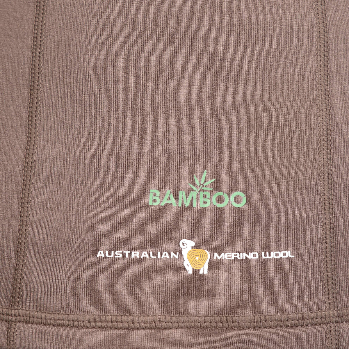 Nahaufnahme eines braunen Stoffes mit dem grünen Text „BAMBOO“ und dem weißen Text „AUSTRALIAN MERINO WOOL“. Dazwischen befindet sich die Abbildung eines Schafs mit Spiralmuster, das die Synergie von Merinowolle und fortschrittlicher SYNERTECH™-Technologie auf dem Hillman 3ML Jagd Hoodie symbolisiert.