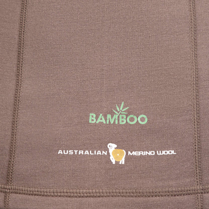 Nahaufnahme eines braunen Stoffes mit dem grünen Text „BAMBOO“ und dem weißen Text „AUSTRALIAN MERINO WOOL“. Dazwischen befindet sich die Abbildung eines Schafs mit Spiralmuster, das die Synergie von Merinowolle und fortschrittlicher SYNERTECH™-Technologie auf dem Hillman 3ML Jagd Hoodie symbolisiert.