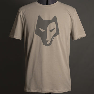Das Hillman Jagdshirt Alpha – Jagd T-Shirt in Beige zeigt in der Mitte ein stilisiertes dunkles Wolfsgesicht. Es ist aus ägyptischer Baumwolle gefertigt und auf einer Schaufensterpuppe mit dunkelgrünem Hintergrund abgebildet, was die Hightech-Produktionsqualität unterstreicht.