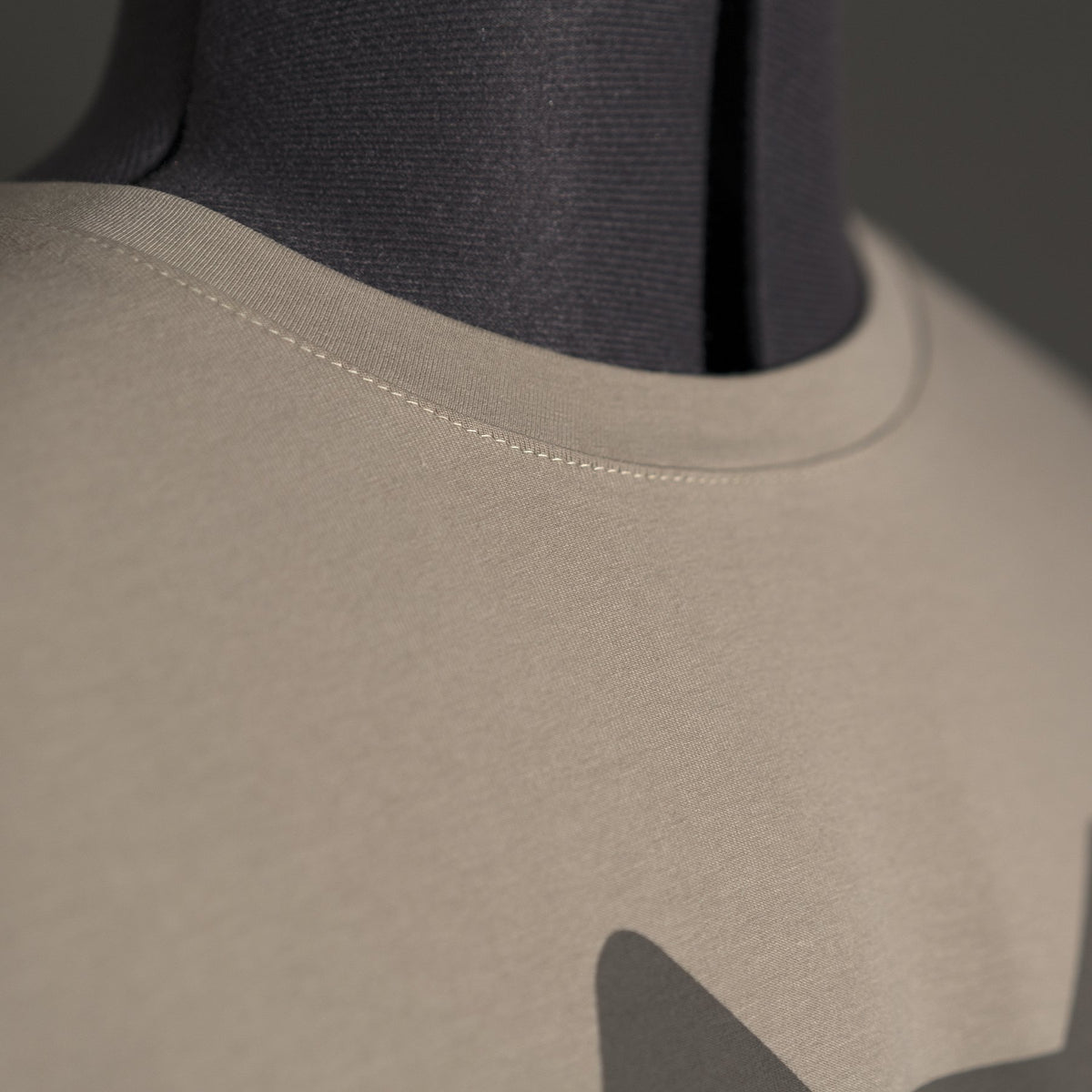 Nahaufnahme des Jagdshirt Alpha – Jagd T-Shirts von Hillman an einer Schaufensterpuppe. Ausschnitt und Schulternaht sind hervorgehoben. Das T-Shirt aus ägyptischer Baumwolle bildet mit seiner glatten Textur einen Kontrast zum dunkelgrauen Hintergrund.